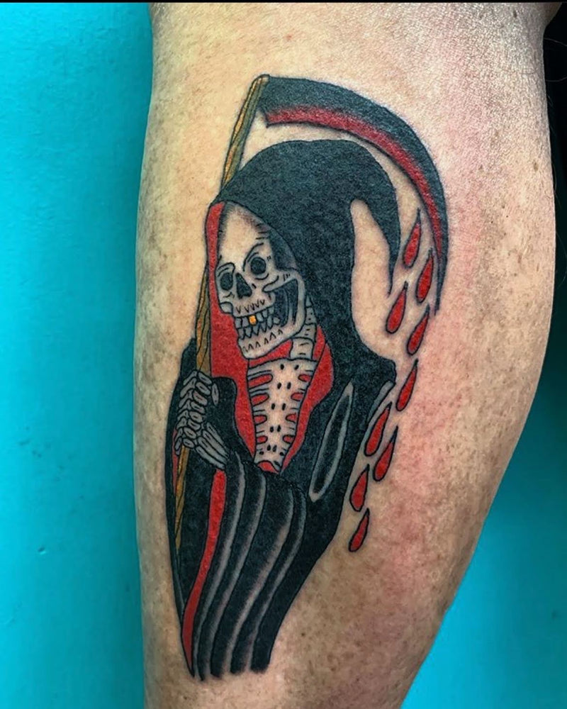 Tattoo of a traditional style Grim Reaper on client’s forearm against a blue background